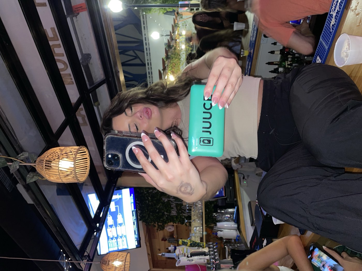 A patron taking a selfie with a JUUCE charger at the bar
